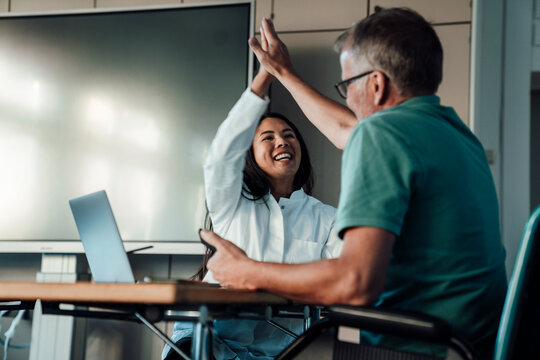 Doctor and patient celebrating success with high five in clinic