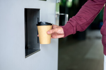 Close up of man's hand buying coffee or hot drink cup from automated beverage maker vending machine.