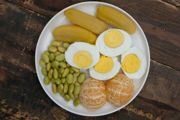 A plate of healthy breakfast. Balance diet. Boiled egg, steamed banana, boiled edamame, tangerine.