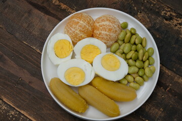 A plate of healthy breakfast. Balance diet. Boiled egg, steamed banana, boiled edamame, tangerine.