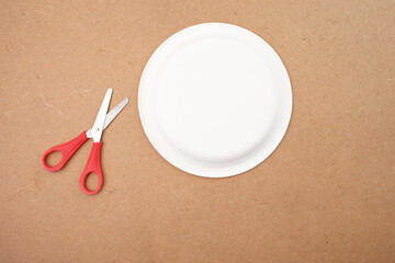 Top view scissors paper plate on brown surface, ideal for craft tutorial, school project, DIY blog,...