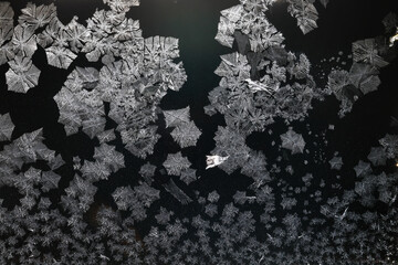 Ice crystals freezing on a black background, abstract winter photo surface