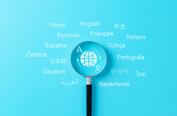Multilingual language translation technology concept. Magnifying glass focusing on global translation icon surrounded by words in various international languages. translate, multilingual communication