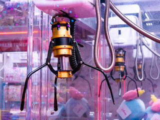 Golden Yellow Claw Grabber Mechanism Inside Arcade Crane Machine with Pink Plush Toys and LED Lights