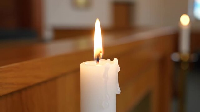 Glowing candle flame in a dim space, focus on the wax drips