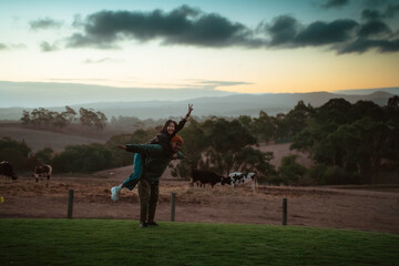 A couple enjoying a playful moment against a beautiful sunset backdrop.