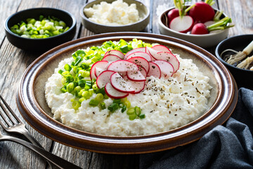 Cottage cheese with scallions and radishes on wooden table
