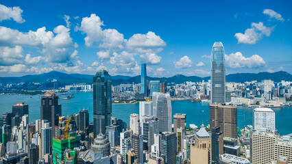Fototapeta premium Latest October 2025 aerial view of Hong Kong business skyscrapers, Victoria Harbour, Kowloon and Hong Kong Island in beautiful clean sky and fluffy cloud