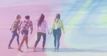 Fototapeta premium Walking four friends strolling barefoot at seaside beach toward horizon with sunglasses