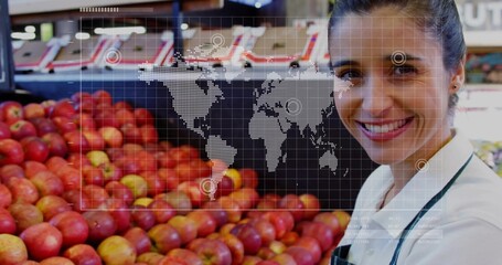 Clerk wearing apron stacking red apple bins at produce aisle, with world map overlay, copy space