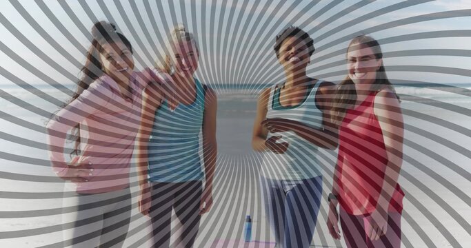 Smiling friends wearing athletic tops and leggings at oceanfront beach, with yoga mat, water bottle - Powered by Adobe