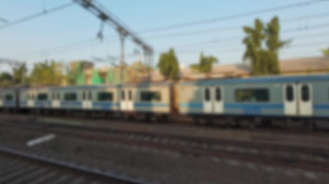 Blurry view of the local train quickly passing by, filmed from the window of another train in Mumbai, India. Real time bokeh motion video for background.