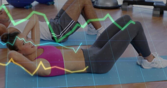 Crunching partners in sportswear doing crunches on blue mats at gym with digital line chart overlay - Powered by Adobe