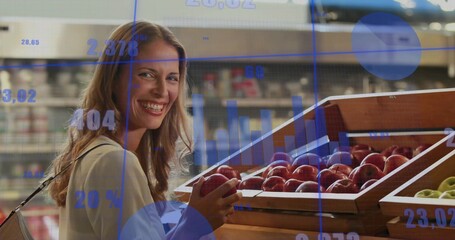 Smiling woman wearing long-sleeve top holding red apple at supermarket bins with data overlays