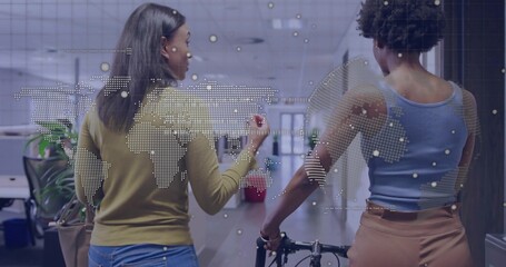 Walking two women coworkers carrying bicycle frame and talking in office corridor, with map overlay