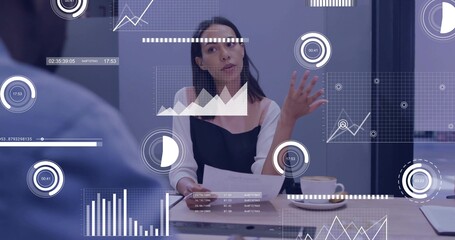 Gesturing executive presenting data at conference table, with printed documents and digital charts