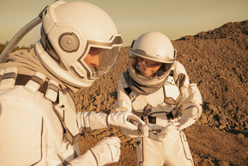 Two astronauts in spacesuits holding soil samples and discussing their findings on the surface of Mars.