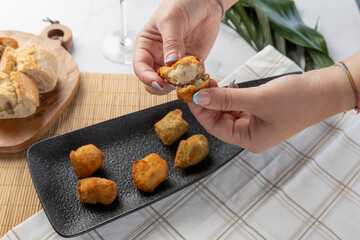 Woman breaking fried croquette showing flavorful inside