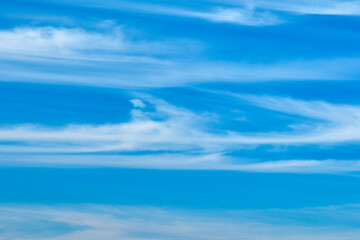 A bright blue sky filled with delicate white cirrus clouds. The scene evokes calm, freedom, and...