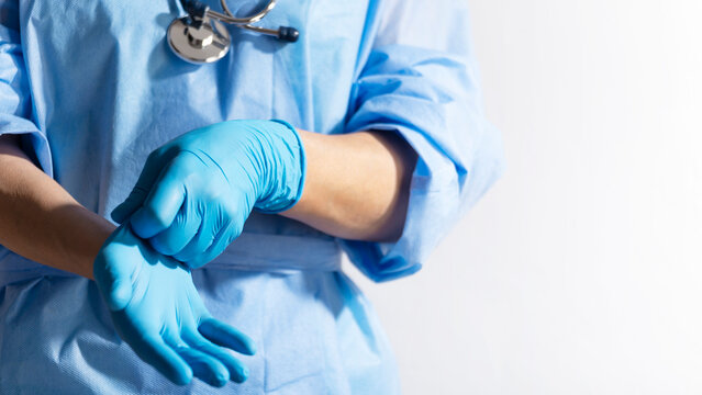 Healthcare professional putting on blue medical gloves on white background with copy space - Powered by Adobe