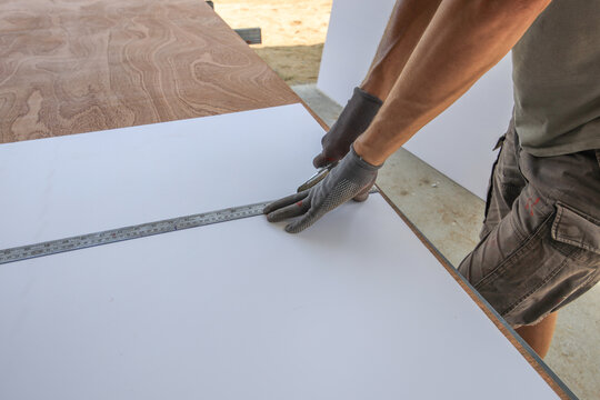 Man is measuring a piece of wood with a ruler