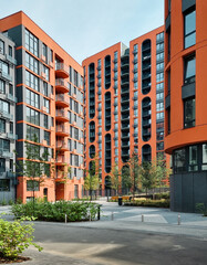 Modern residential building with orange facade. District with residential high-rise buildings on sunny day. 