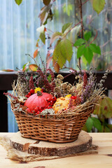 Florist at work: woman shows how to make seasonal autumn table decoration with pumpkins, flowers and plants in a wicker basket.