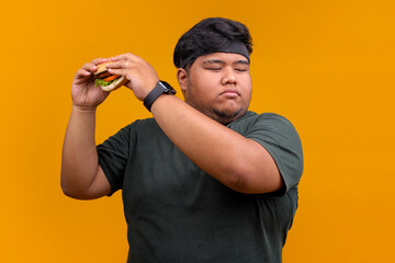 Naklejka premium Overweight Man with Eyes Closed About To Eat Burger, Representing Unhealthy Eating Habits and Desire