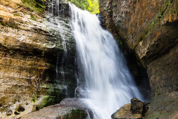 Waterfall and cliff surrounded by greenery in summer