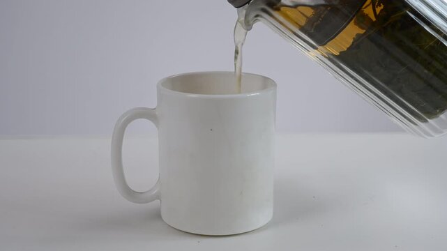 A man pours tea from a French press. Video with sound.