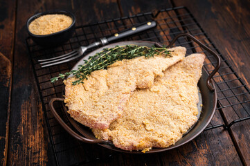 Viennese breaded raw Schnitzel steak on a tray. wooden background. top view