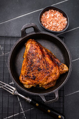 Fried roasted chicken thigh in a skillet, eco poultry meat. black background. top view