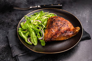 Roasted chicken thigh with salad on a plate, poultry meat. black background. top view