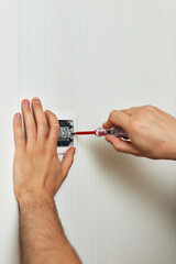 electrician installing electric light switch using screwdriver at home, close-up