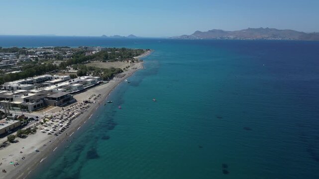 Aerial view of a sun-kissed beach with sunbathers, contrasted by the turquoise sea meeting the shore, Kos, Greece.