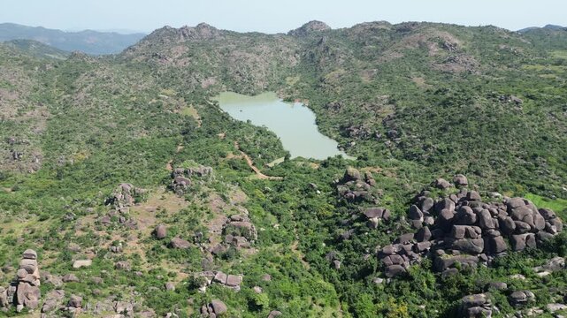 Aerial view of the rugged Shere Hills, where a serene lake nestles amidst verdant vegetation and rocky outcrops, creating a stunning contrast, Shere Hills, Plateau, Nigeria.