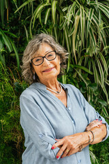 Senior woman smiling standing in front of green wall