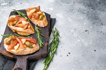 Tapa with Jamon cured ham, parmesan cheese and olives. grey background. top view