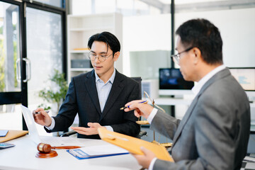 Lawyer consulting client in modern office, reviewing documents with gavel and scales on desk. Ideal for law, finance, consulting, or corporate themes.