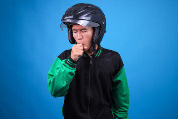 Asian Motorcycle Taxi Driver in Jacket and Helmet Covering His Mouth While Coughing Showing Discomfort or Sickness