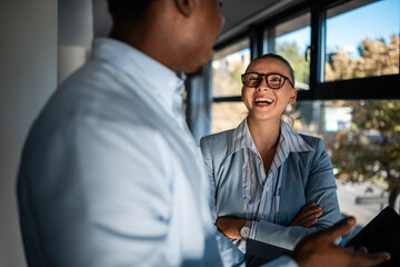 Happy business colleagues sharing lighthearted conversation at office