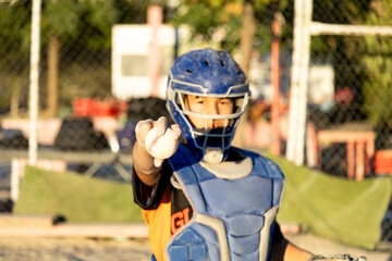 Young baseball catcher proudly holding ball on field