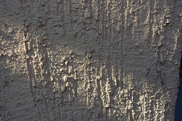 Construction materials, materials for finishing walls. Bark beetle, shirpa sand on a wall painted with brownish-gray paint, reliefs, recesses, bulges.