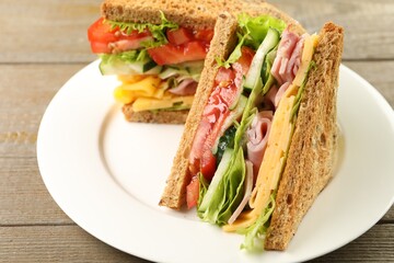 Tasty sandwiches with ham, cheese and vegetables on wooden table, closeup