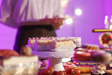 Different delicious desserts on buffet table and waiter, selective focus
