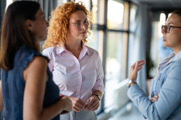 Businesswomen having serious discussion in modern office hallway