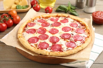 Delicious pepperoni pizza and ingredients on wooden table, closeup