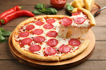 Taking piece of delicious pepperoni pizza at wooden table, closeup