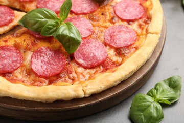 Delicious pepperoni pizza with fresh basil on grey table, closeup