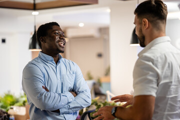 Happy colleagues having friendly conversation in modern office